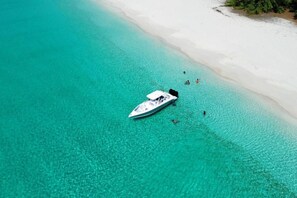 A boat anchored near a white sandy beach with clear turquoise water. - Turks & Caicos Retreat | 1BR Private | Experiences (Providenciales)