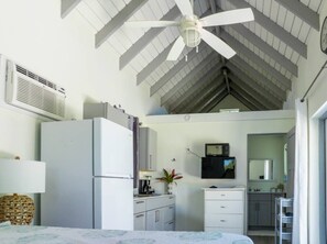 A compact kitchen with a refrigerator, microwave, and a small dining area with a table and chairs. - Turks & Caicos Retreat | 1BR Private | Experiences (Providenciales)