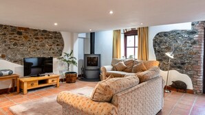 Ein gemütliches Wohnzimmer mit Steinwand, Kamin, einer Couch, einem Fernseher und einem Holzschrank.