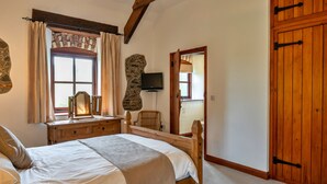 Ein Schlafzimmer mit Bett, Kommode, Spiegel und einer Steinwand.