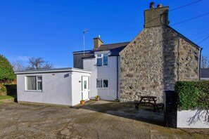 A two-story house with a stone exterior and a small attached garage. - Beachfront Llyn Peninsula Cottage for 6 (Pwllheli)
