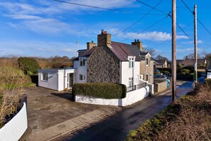 A residential property with a stone facade, a small attached garage, and a paved driveway. - Beachfront Llyn Peninsula Cottage for 6 (Pwllheli)