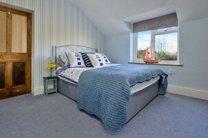 Un dormitorio con cama, mesita de noche, ventana con vistas y puerta.