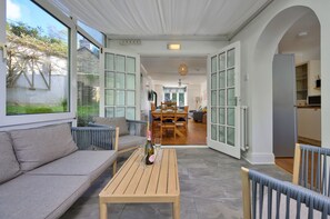 A spacious living area with a sofa, a wooden table, and a dining table with chairs. - Chic Country Club Lodge With Hot Tub (Harlech)