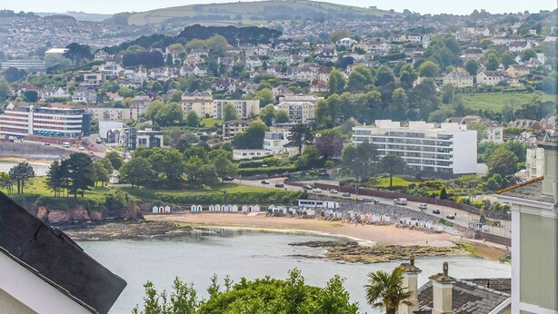 A coastal town with residential buildings, a beach, and a hill in the background. - The Maycliffe - Compact Studio Close to Beach (Torquay)