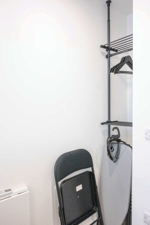 A room with a wall-mounted drying rack, a folding chair, and a radiator.