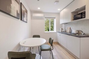 Eine kleine Küche mit rundem Tisch und Stühlen, einem Fenster und integrierten Geräten.
