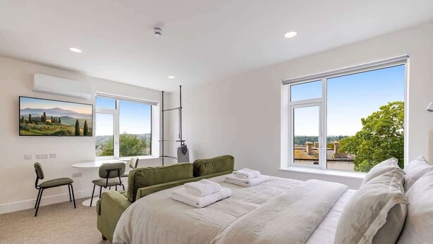 A modern bedroom with a large bed, a desk, and a chair. - The Maycliffe - Bright Contemporary Studio (Torquay)