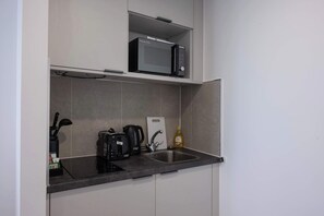 Eine kleine Küche mit Mikrowelle, Toaster, Wasserkocher und einer Flasche Kochöl.