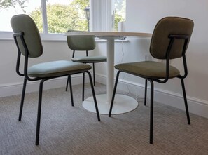 Ein Zimmer mit einem runden Tisch und vier Stühlen mit Metallgestellen und gepolsterten Sitzflächen.