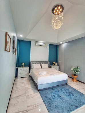 Quarto moderno com uma cama grande, uma parede de destaque azul e um candeeiro de teto.