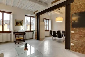 Ein geräumiges Zimmer mit Essbereich, einem Glastisch und einer Ziegelwand.