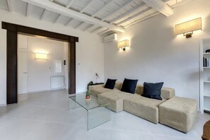 A modern living room with a sectional sofa, glass coffee table, and built-in shelving. - Luxury Renovated Apartment with Lift Near Santo Spirito - Sleeps 7 (Firenze)