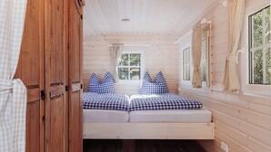 Interior acogedor de una cabaña con cama, paredes de madera y una ventana con cortinas.