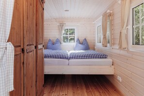 Interior acogedor de una cabaña con cama, paredes de madera y una ventana con cortinas.