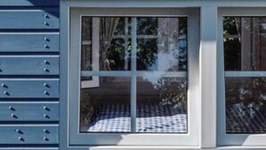 Una ventana con vista a una mesa a cuadros y árboles.