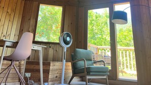 A wooden interior with a high ceiling, a fan, a green chair, and a desk.