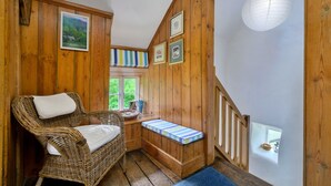 Un intérieur en bois avec une chaise en osier, une fenêtre, un escalier et une lanterne en papier blanche.
