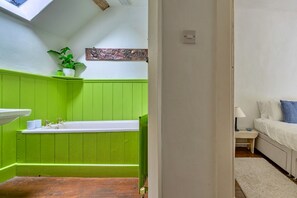 Ein Badezimmer mit einem grünen Waschtisch, einem weißen Waschbecken und einem kleinen Topfpflanzen.