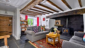 Un salon chaleureux avec une cheminée, un canapé, une table basse et une bibliothèque.