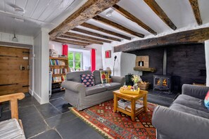Ein gemütliches Wohnzimmer mit Kamin, einer Couch, einem Couchtisch und einem Bücherregal.