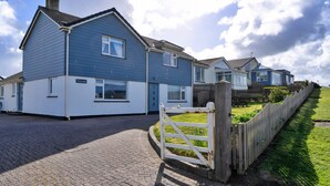 A residential area with houses, a paved driveway, and a wooden fence. - Kingsand Coastal Retreat for 6 (Bude)