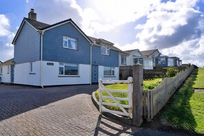 A residential area with houses, a paved driveway, and a wooden fence. - Kingsand Coastal Retreat for 6 (Bude)