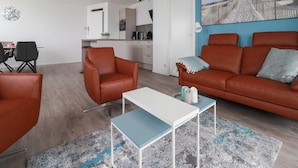 A modern living room with a sofa, armchairs, a coffee table, and a dining area with chairs and a table. - Sun-facing Apartment With Ijsselmeer Views (Makkum)