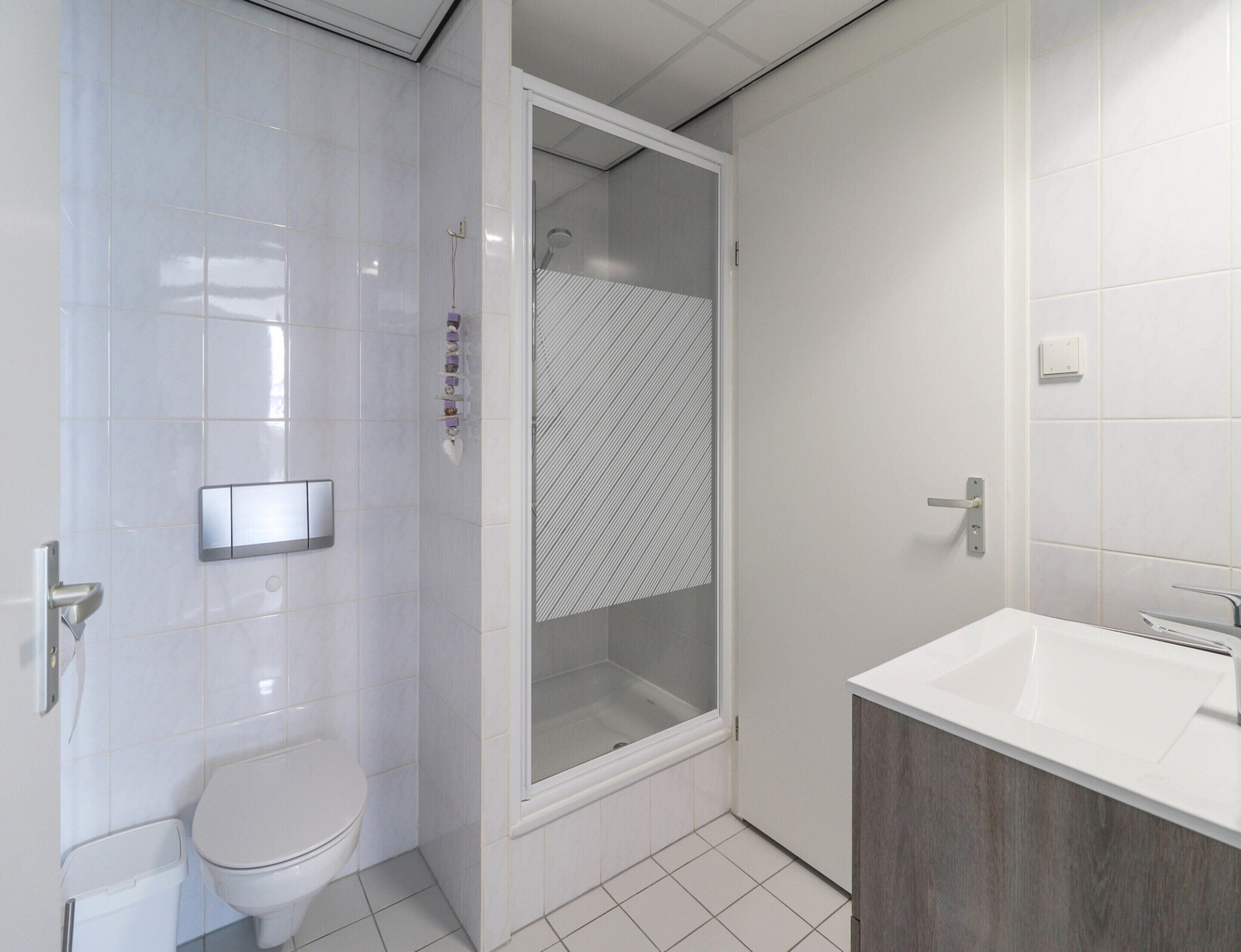 Un baño moderno con inodoro, cabina de ducha y lavamanos.