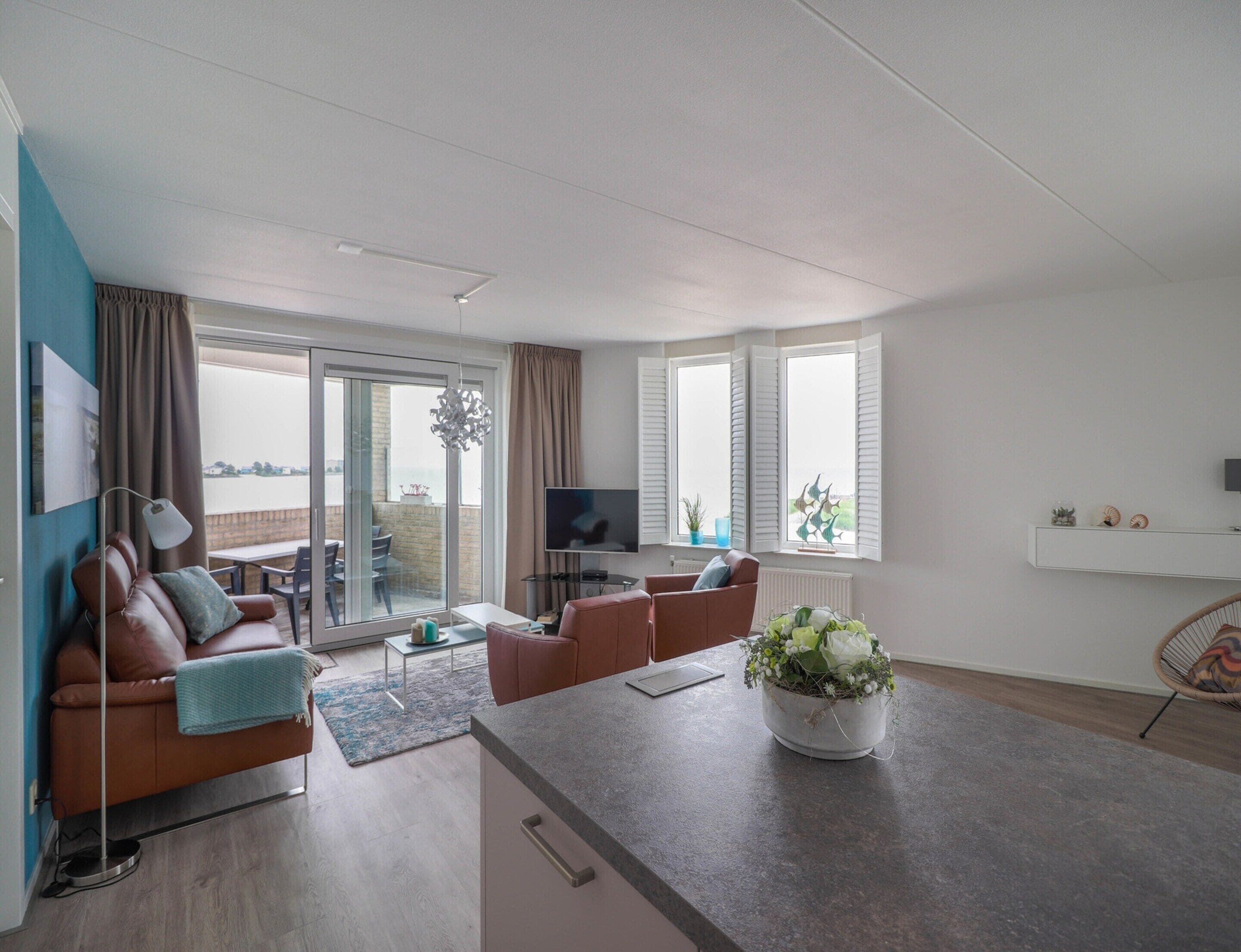 A modern living room with a sofa, a coffee table, a TV, and a balcony view.