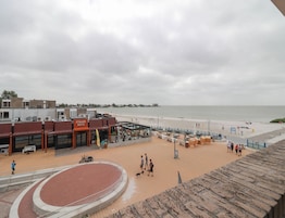 Uma área à beira-mar com pista de corrida, mesas ao ar livre e um restaurante chamado 'STRAND HUYS'.