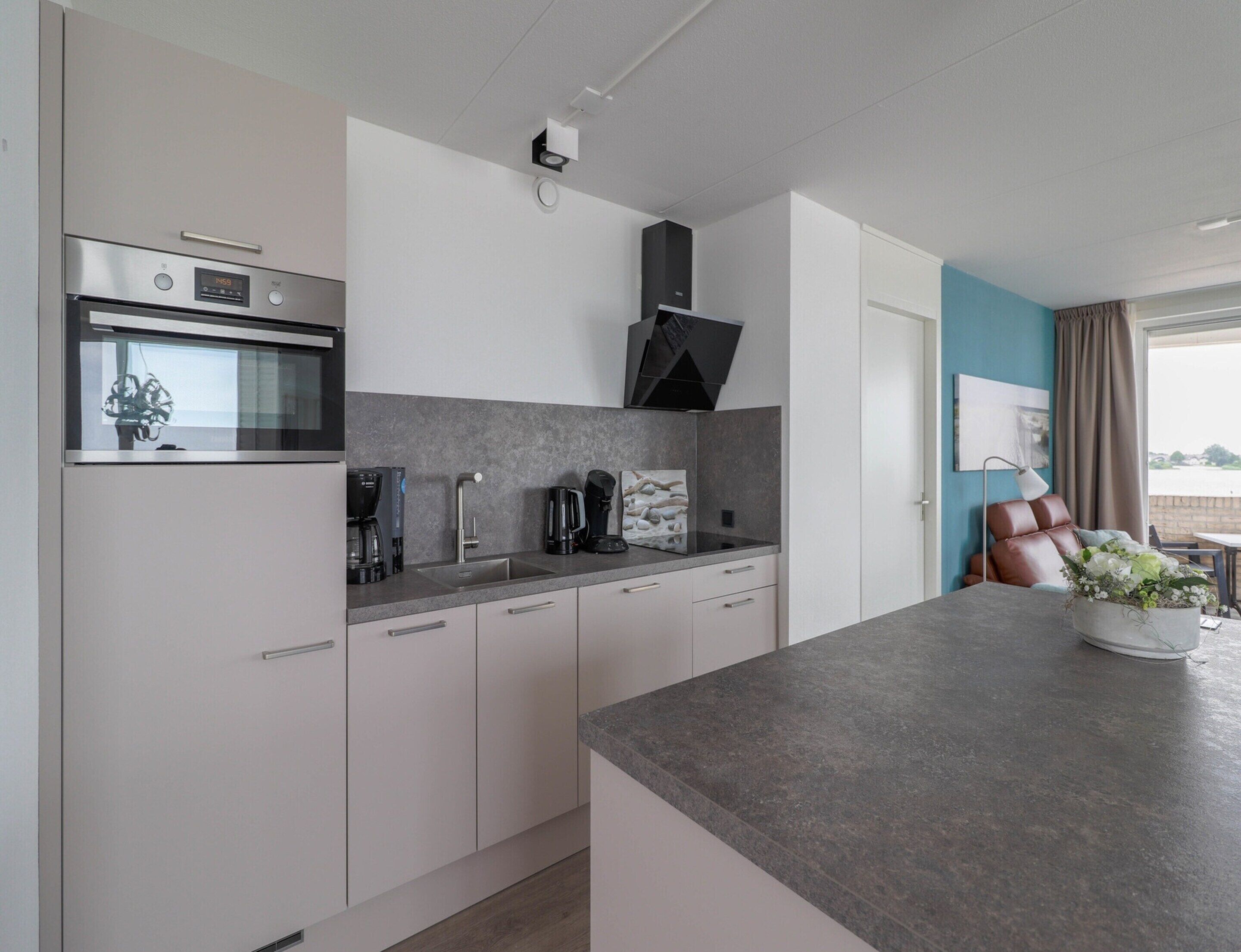 Una cocina moderna con horno integrado, cafetera y lavabo.