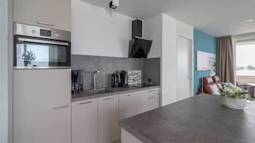 Una cocina moderna con horno integrado, cafetera y lavabo.