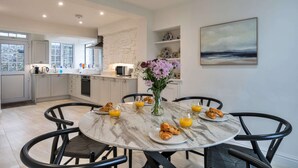 Una cocina moderna con comedor, que incluye una mesa de mármol, sillas y un jarrón con flores.