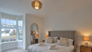 Un dormitorio con una cama grande, dos mesitas de noche, un espejo y una ventana con vistas.