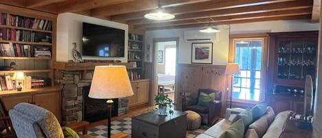 A cozy living room with a fireplace, a television, and a bookshelf.