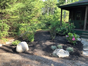 A garden with a gravel path, large rocks, and various plants.