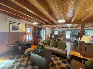 L’intérieur d’un chalet accueillant, avec un sol à carreaux, des murs en bois, un canapé, une table à manger et un coin cuisine.