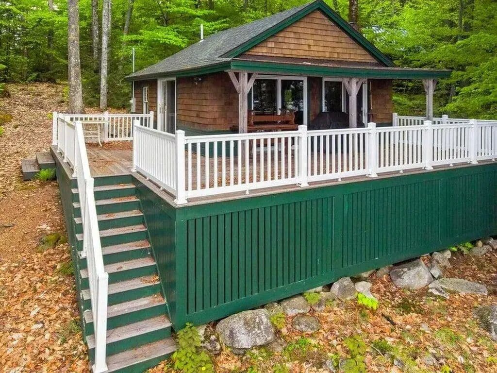 A cabin with a porch, a staircase, and a fenced deck.