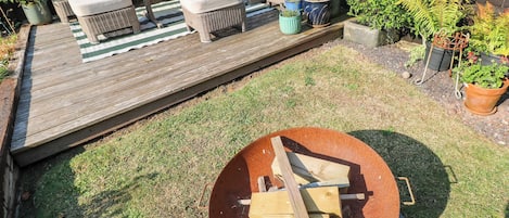 Een houten terras met tuinmeubilair, een vuurkorf en potplanten.