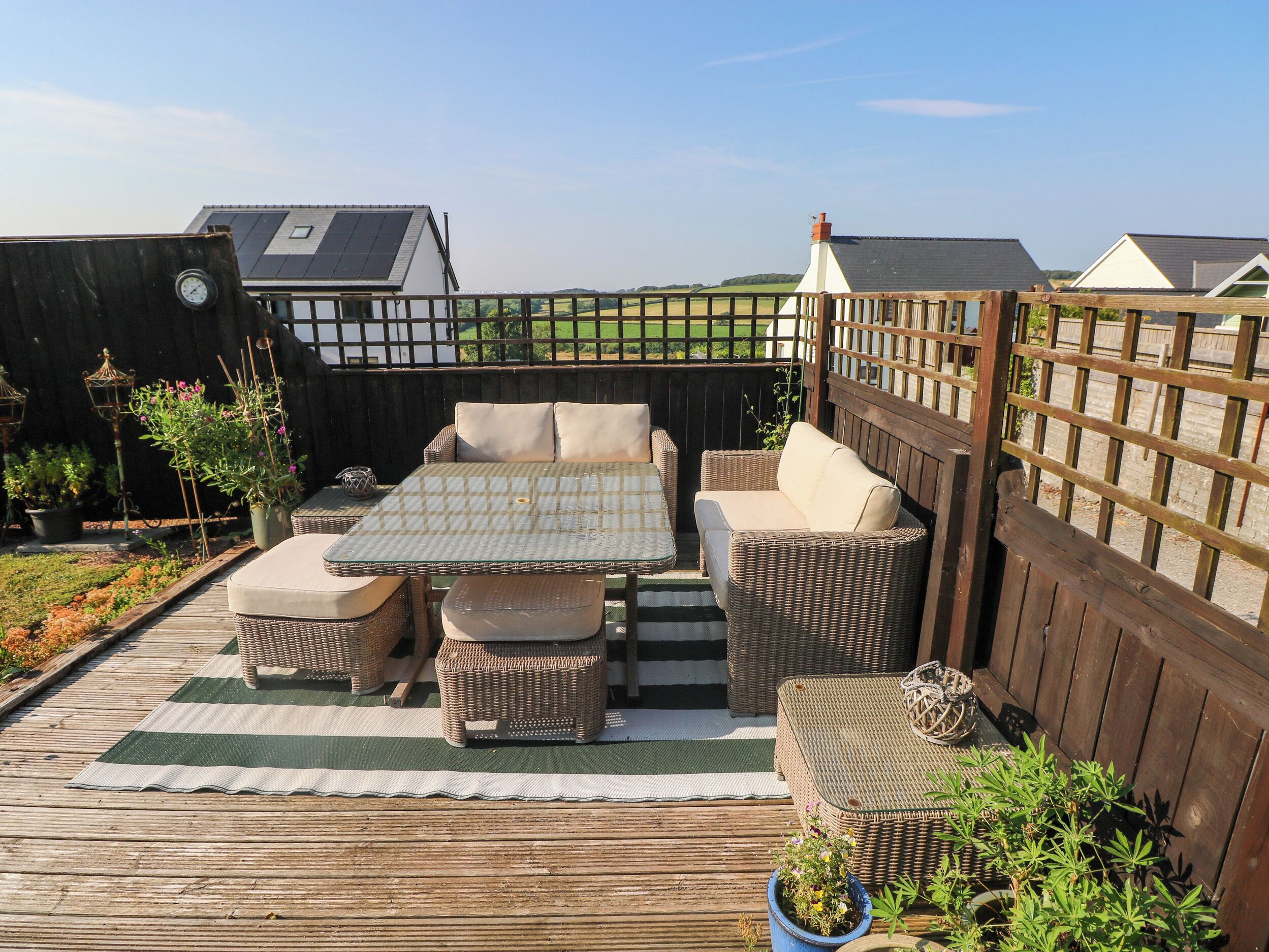 An outdoor patio with a table and chairs, surrounded by a wooden fence, and a view of houses in the background.