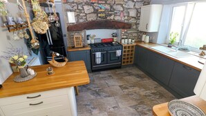 A kitchen with a stone wall, wooden countertop, and a built-in oven. - St.twynells Farm (Pembroke)