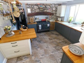 A kitchen with a stone wall, wooden countertop, and a built-in oven. - St.twynells Farm (Pembroke)