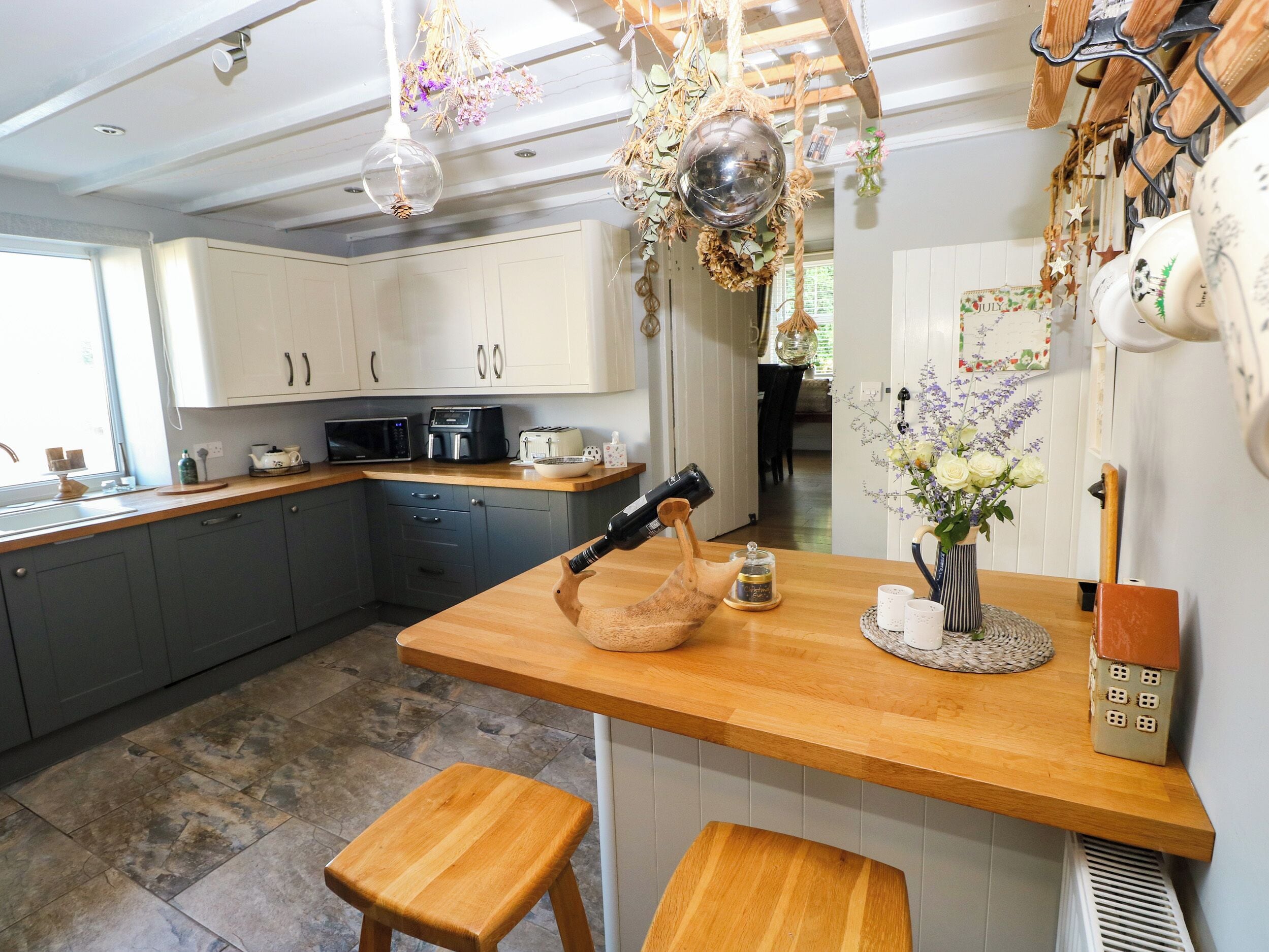 A kitchen with a wooden countertop, a sink, cabinets, and a dining area with a table and chairs.