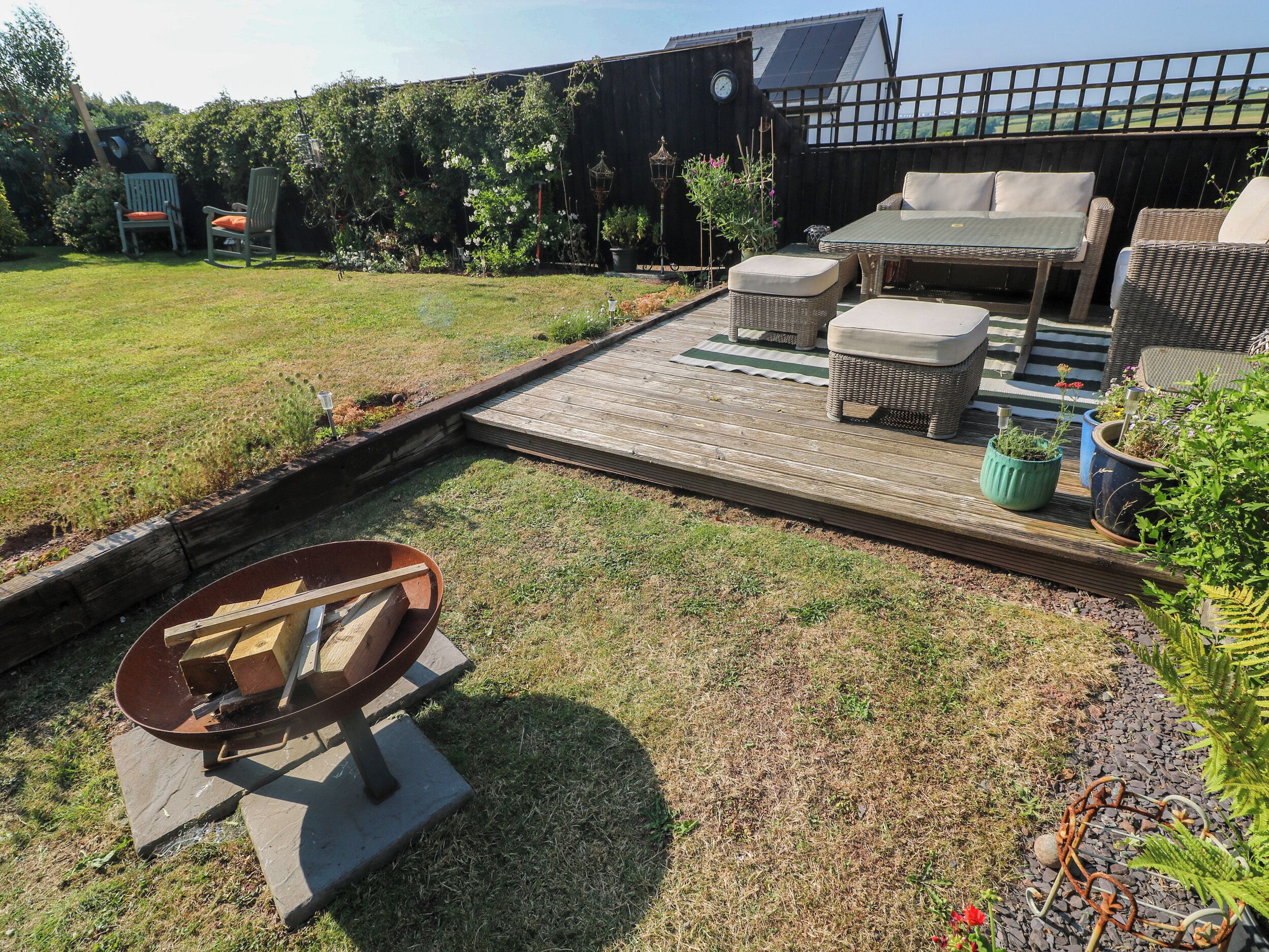 Un espace patio aménagé avec du mobilier d’extérieur, un foyer et une terrasse en bois.