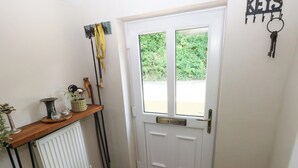 A white door with a window, a wooden shelf with decorative items, and a key holder on the wall. - St.twynells Farm (Pembroke)