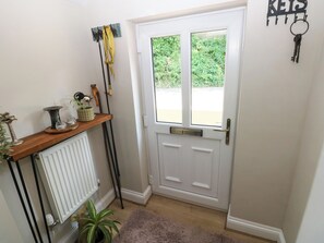 A white door with a window, a wooden shelf with decorative items, and a key holder on the wall. - St.twynells Farm (Pembroke)