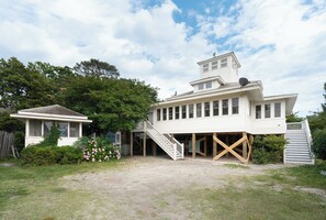 Una casa de dos pisos con un porche cubierto y un edificio pequeño contiguo.