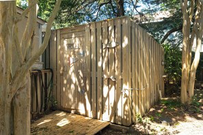 Un capanno di legno con una porta e una piccola rampa di accesso, circondato da alberi.