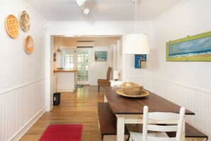 En matplats med ett träbord, vita stolar, en röd matta och en lampa.